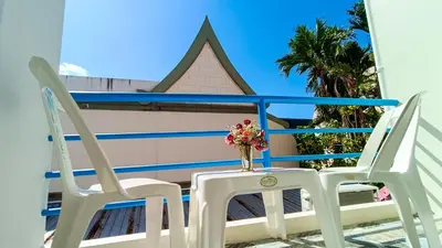 two chairs and a vase with flowers on a balcony at Kata Lina guesthouse in Kata Beach