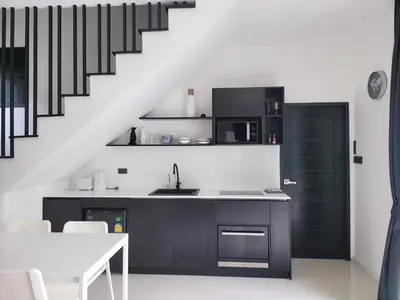 a kitchen with black cabinets and a staircase at Villa Coco - Tropical Paradise with Private Pool in Thalang