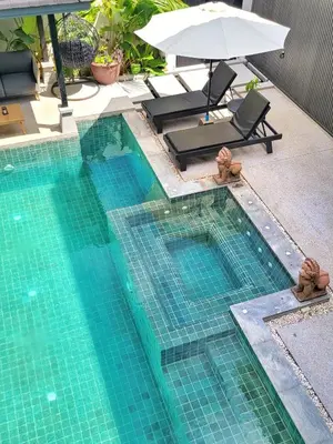 a swimming pool with a chair and an umbrella at Villa Coco - Tropical Paradise with Private Pool in Thalang
