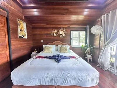 a bedroom with a large bed with wooden walls at บ้านสวนปิยนันท์ (Baansuan Piyanan) in Ko Yao Noi
