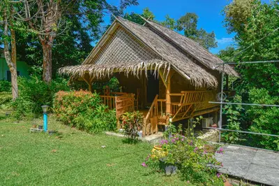 a hut with a thatched roof in a yard at Ratanaporn Green in Phuket Town