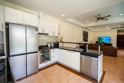 a kitchen with white appliances and a living room at Grand 4-Bed Lagoon Villa - Private Pool & Garden - Laguna in Ban Thalat Choeng Thale