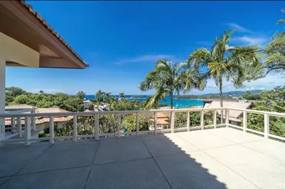 a balcony with a view of the ocean and palm trees at Scenic Seaview Villa Sea Dream for 9, Tennis Court, 5min walk to Kata Noi Beach in Kata Beach