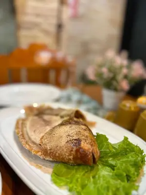 a fish on a plate with lettuce on a table at BT hotel Kata Beach in Kata Beach