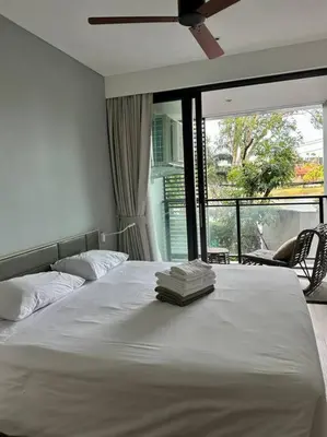 a bedroom with a white bed with a large window at Cassia Residences in Phuket Town