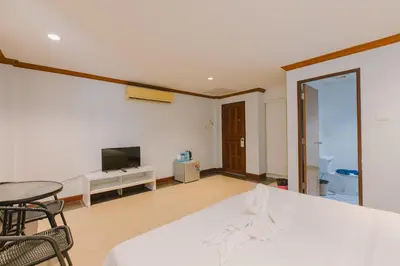 a living room with a white bed and a tv at Sunstar Palace Patong in Patong Beach