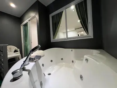 a white bath tub in a bathroom with a mirror at Zephyr Grand Hotel in Patong Beach