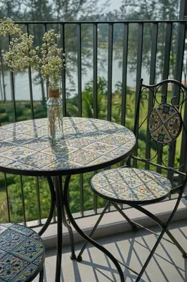 a table and chairs with a vase of flowers on a balcony at Modern 2-bedroom Apartments Garden view in Skypark Laguna Bang Tao in Bang Tao Beach