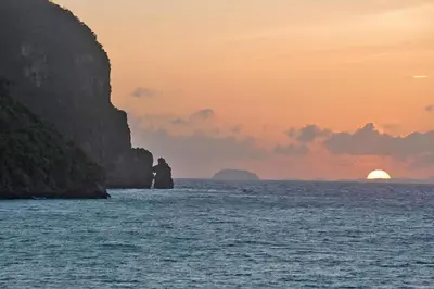 a boat in the ocean with a sunset in the background at The Cobble Beach Hotel- Phi Phi Island in Phi Phi Don