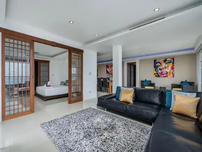 a living room with a black leather couch at The Blue Bay Experience in Kata Beach