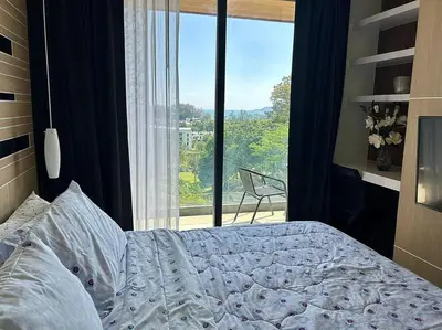 a bedroom with a bed and a large window at Calypso rawai seaview apartment 600m walk to beach C4 in Phuket Town
