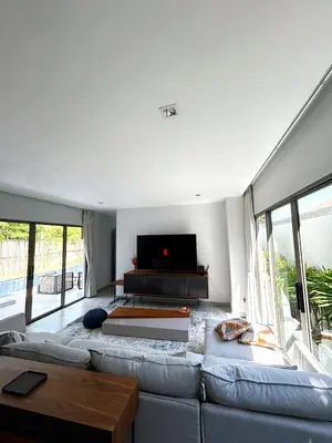 a living room with a couch and a flat screen tv at A spacious Balinese style villa with a large swimming pool on Rawai an electric motorcycle as a gift! in Ban Saiyuan (1)
