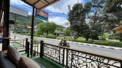 a man riding a motor scooter on a balcony at Coco Mountain View Guest House Hotel in Kata Beach