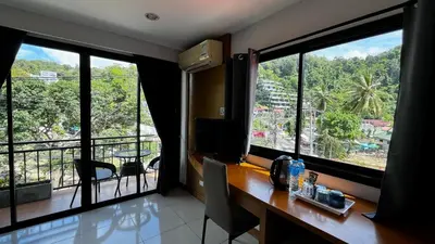 a room with a desk with two large windows at Coco Mountain View Guest House Hotel in Kata Beach