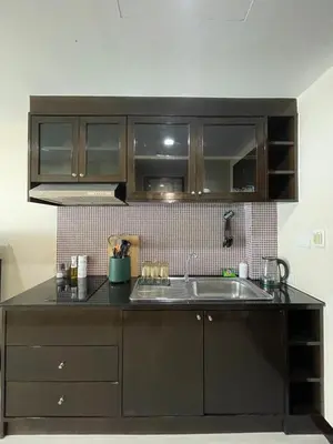 a kitchen with a sink and wooden cabinets at The Kris 2 Bedrooms 2 Bathrooms Apartment in Patong Beach