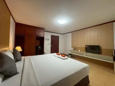 a bedroom with a large white bed and a flat screen tv at Priew Wan Guesthouse in Patong Beach