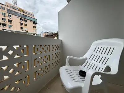 a white bench sitting on a balcony with a building at Priew Wan Guesthouse in Patong Beach