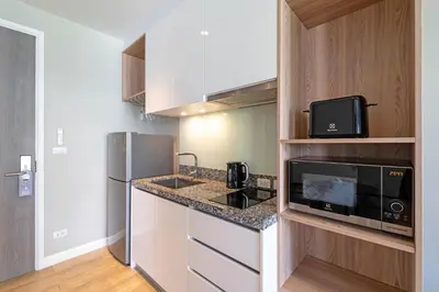 a small kitchen with a microwave and a refrigerator at Bangtao Beach Apartments in Bang Tao Beach