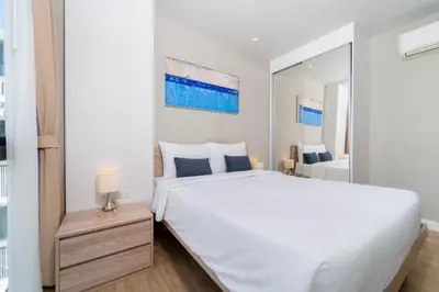 a bedroom with a large white bed and a mirror at Bangtao Beach Apartments in Bang Tao Beach