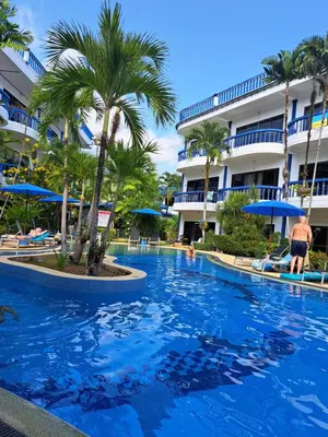 a pool at a resort with palm trees and a building at Homely with pool near the beach in Kamala Phuket in Kamala Beach