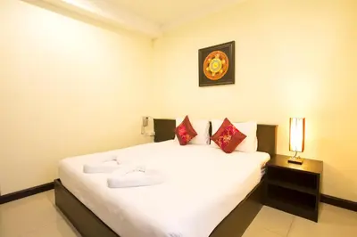 a bedroom with a large white bed with red pillows at The Elegant Patong in Patong Beach