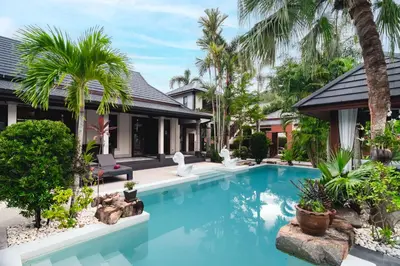 a swimming pool in front of a house with palm trees at Villa Banyak Luxury 4Br villa with nice terrace in Rawai Beach