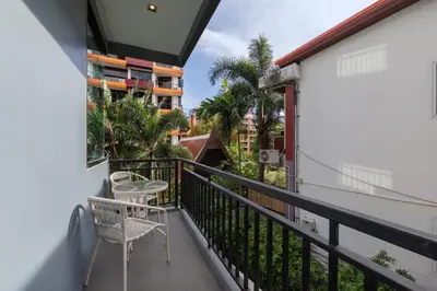 a balcony with a chair and a table and a building at Modern studio at Relife 2 min to Nai Harn beach in Rawai Beach