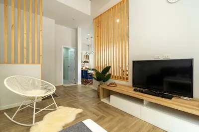 a living room with a large television and a chair at Naka Cozy House in Phuket City in Ban Rangeng