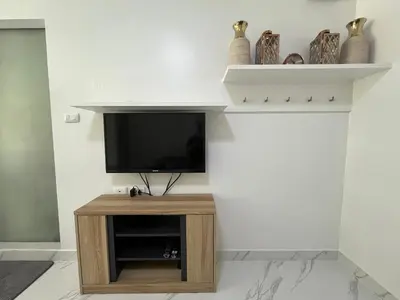 a living room with a flat screen tv on a wall at Cozy and delightful room with pool view in Kathu