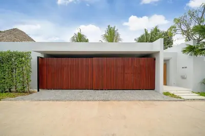 a red garage door on a white house at Spacious Mansion 4BR Villa Anchan V20 with 15m Private Pool in Gated Residence in Bang Tao Beach