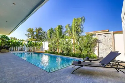 a swimming pool with a chair next to a building at Sweet Luxury by G Estate Phuket in Ban Saiyuan (1)