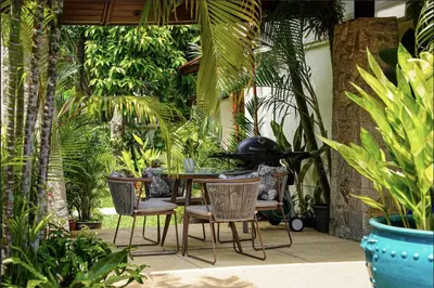 a patio with a table and chairs and plants at Saitaan Villa Dennapa Bang Tao Beach in Bang Tao Beach