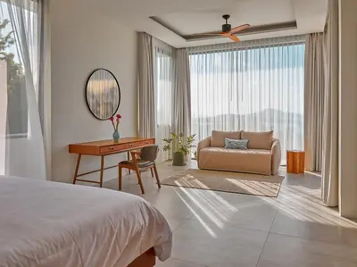 a bedroom with a bed and a desk and a chair at Casa Alma by Elite Havens in Nai Harn Beach
