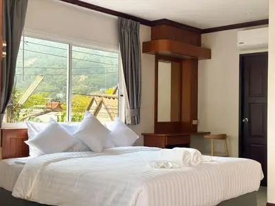 a bedroom with a large bed with a large window at Botanic Boutique Hotel Surin Beach in Bang Tao Beach