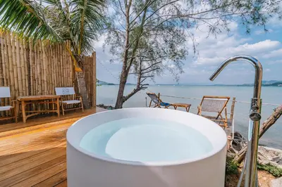 a bath tub on a deck with a view of the water at Sea Sand See Sky Beach Front Resort in Phuket Town