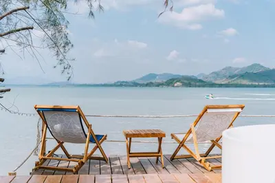two chairs and a table on the beach at Sea Sand See Sky Beach Front Resort in Phuket Town