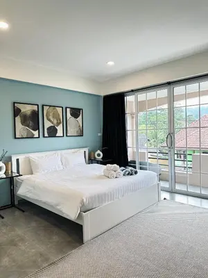 a bedroom with a large white bed with blue walls at Gloria’s Home in Kamala Beach