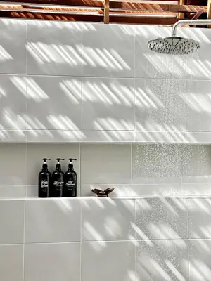 a white tiled bathroom with three bottles on a shelf at 2BR Pool Villa&Garden - Bali style by La Perla Phuket Rawai in Ban Saiyuan (1)