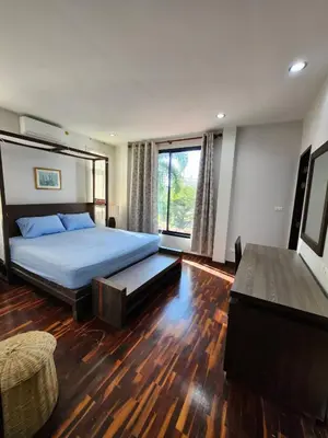 a bedroom with a bed and a large window at KRAAM VILLAS in Thalang