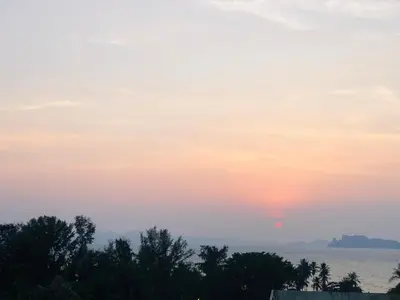 a sunset over the water with trees in the foreground at NAKA GUEST HOUSE in Ban Ko Kwang