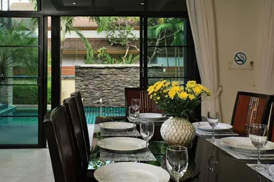 a table with plates and glasses and a vase with flowers at VILLA Salika Thai Balinese pool villa RAWAI in Rawai Beach