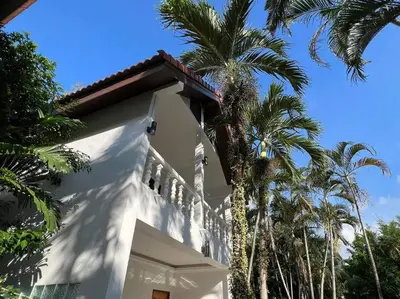 a white house with palm trees in front of it at Charming Villa Suite with Balcony near Beach in Patong Beach