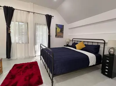 a bedroom with a bed with blue sheets and yellow pillows at Charming Villa Suite with Balcony near Beach in Patong Beach