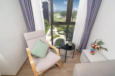 a living room with a chair and a large window at Laguna BangTao Beach Skypark Apartment in Phuket Town