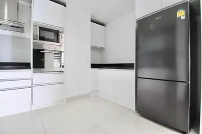 a stainless steel refrigerator in a kitchen with white cabinets at Luxury Rooftop Penthouse in Kamala Beach