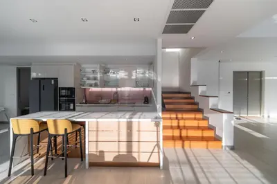 a kitchen with a bar with chairs and a staircase at 5 Bdr 18 meter Pool villa in Laguna Phuket in Phuket Town