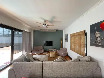a living room with a couch and a tv at Villa KEWALYN in Chalong