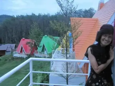 a woman standing on the balcony of a house at Kanda Hill Resort in Ban Na Sok