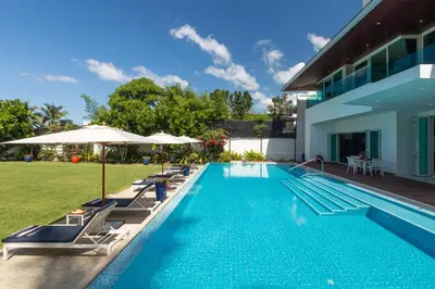 a swimming pool with chairs and umbrellas next to a house at Summer Estate Villa in Pilai Beach