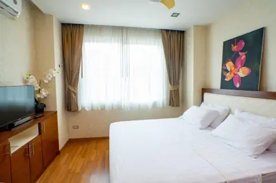 a bedroom with a white bed and a television at Seaside Haven Karon in Karon Beach